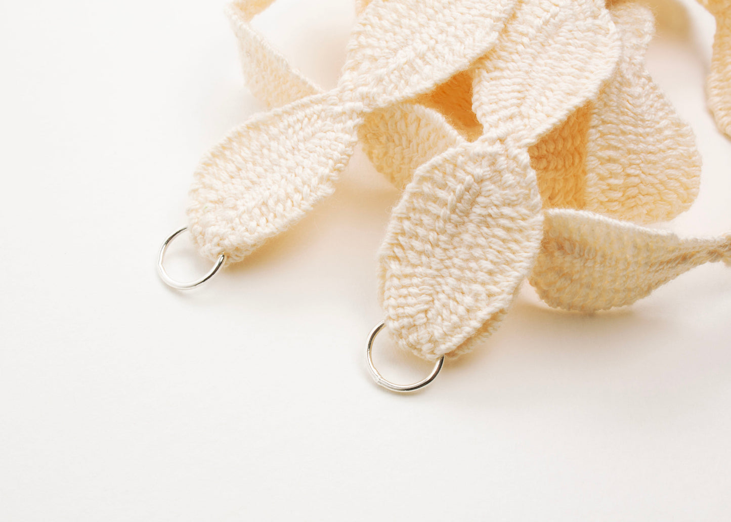 Close up of Sterling Silver endings of a ivory white cotton ovals necklace on a white background
