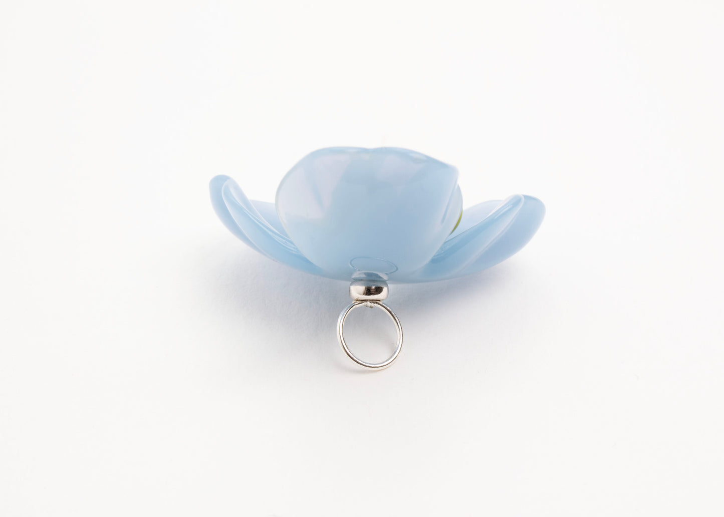 Full back close up of a light blue resin_flower charm with celery green glass bead detail_and a Sterling Silver looped ending on a white background