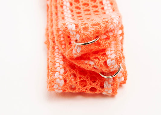 Close up of Sterling Silver looped endings detail of a cotton fishnet ribbon in orange and white on a white background