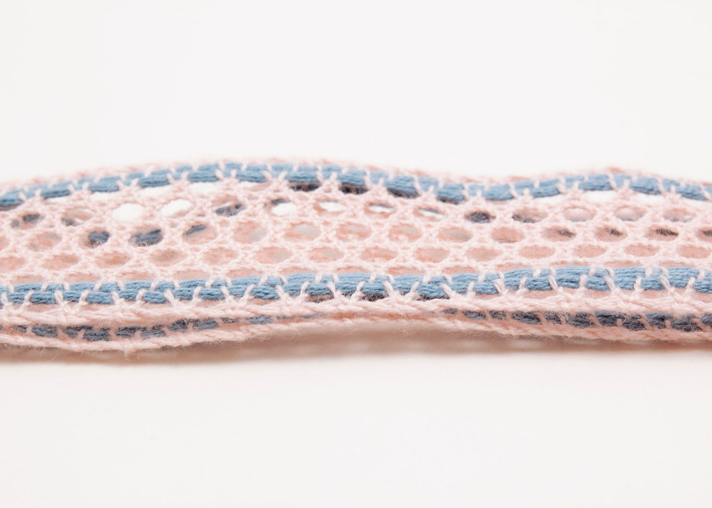 Close up detail of fabric of a cotton fishnet ribbon in pink and light blue with Sterling Silver looped endings on a white background