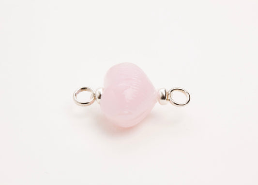 Horizontal close up of pink glass heart charm placed on white background.