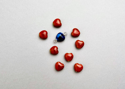 Overhead view of a group_of_red_chunky_porcelain hearts and_a_blue_one_with_Sterling Silver ends_on a great background