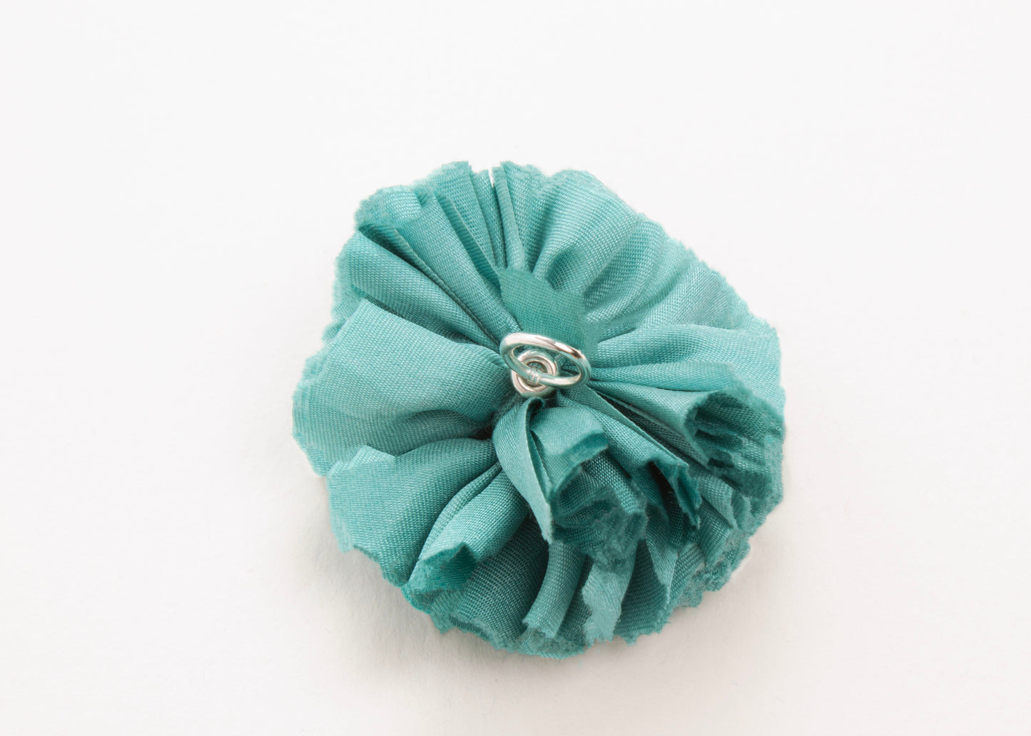 Teal flower connector and charm with sterling silver looped ending on a white background