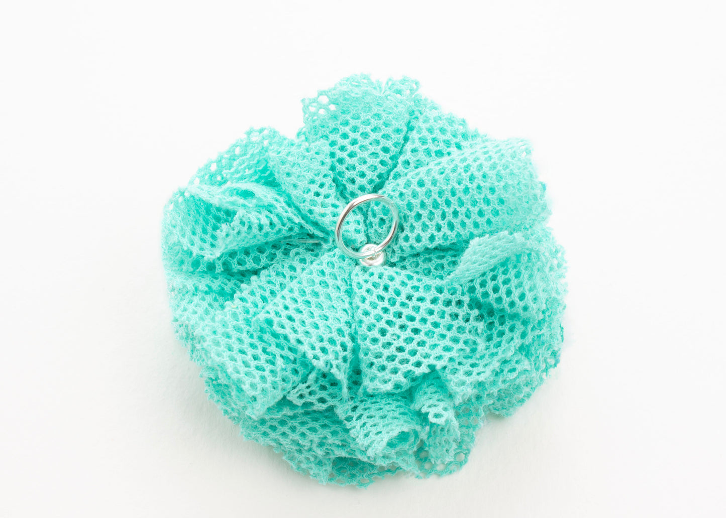 Back view of a turquoise point de tulle flower charm with Sterling Silver ending on a white background