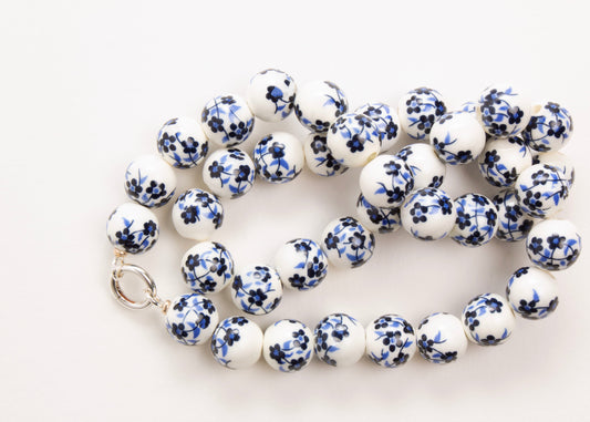 Plan view of a white porcelain with blue hand painted flowers and Sterling Silver looped endings on a white background
