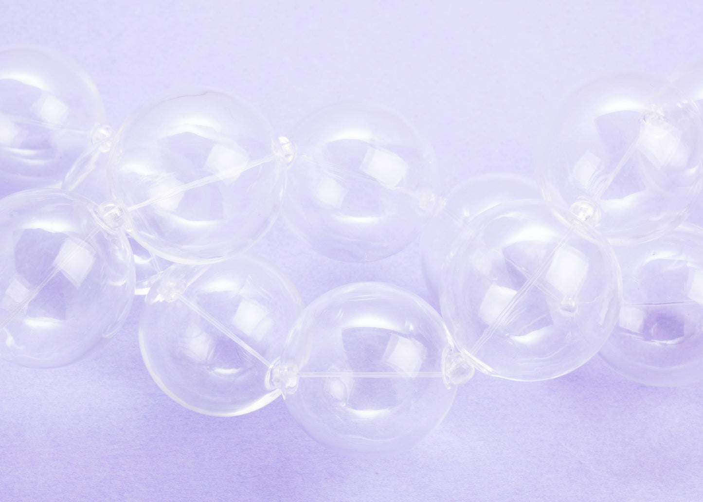 Front view of twisted strands of a chunky clear blown glass beads necklace on a lavender background