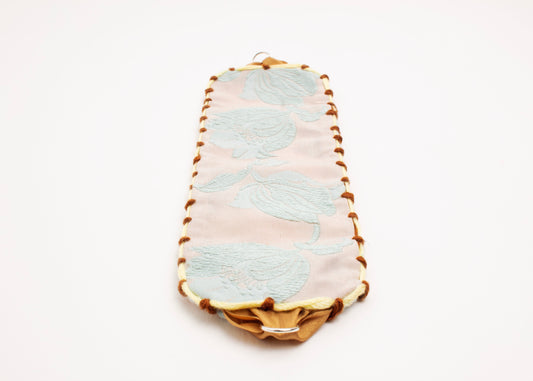 Front view of an open reversible cotton woven strap bracelet with tulip motif in light blue and embroidered borders in brown and butter yellow with Sterling Silver looped endings detail on a white background.