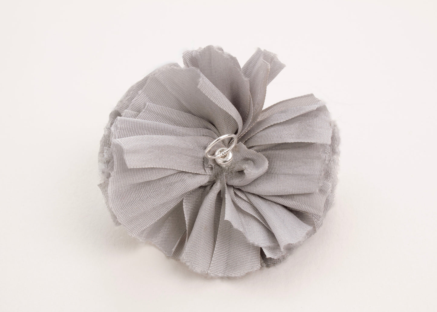 Back view of a silver silk flower charm with sterling silver loop ending on a white background.
