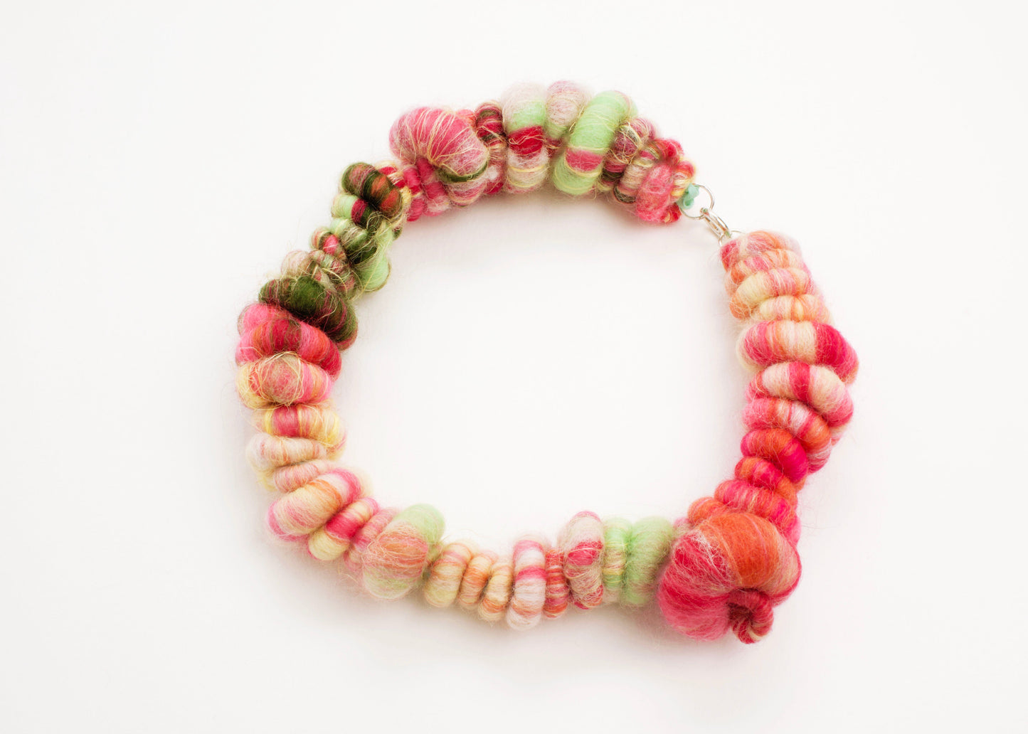 Plan view of a wool yarn closed necklace in persimmon, peach, butter yellow, mint and forest green and Sterling Silver looped endings on a white background