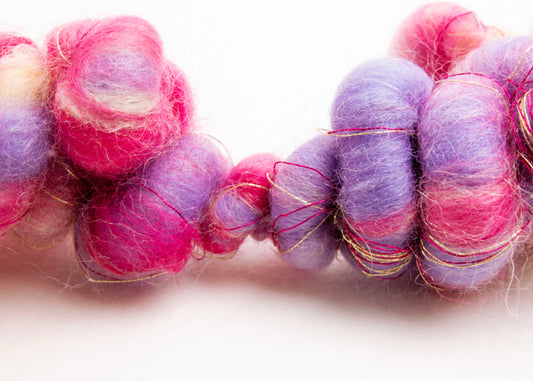 Front view of a wool yarn closed necklace in cream, lavender, deep pink, purple and gold on a white background
