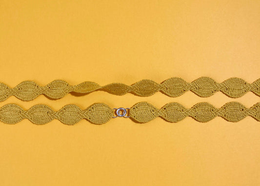 Overhead close look at the fabric and endings of a yellow cotton woven necklace placed horizontally with sterling silver endings on a yellow background