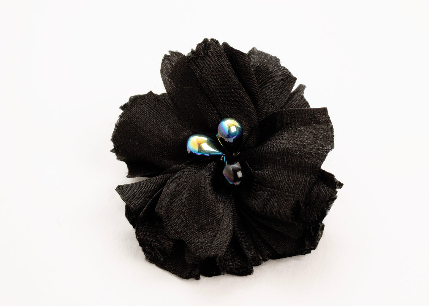 Front view of a black silk flower charm with glass detail in center on a white background.