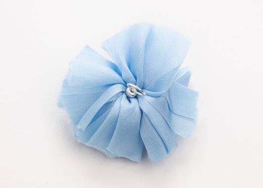 Back view of a cerulean silk flower charm with sterling silver loop ending on a white background.