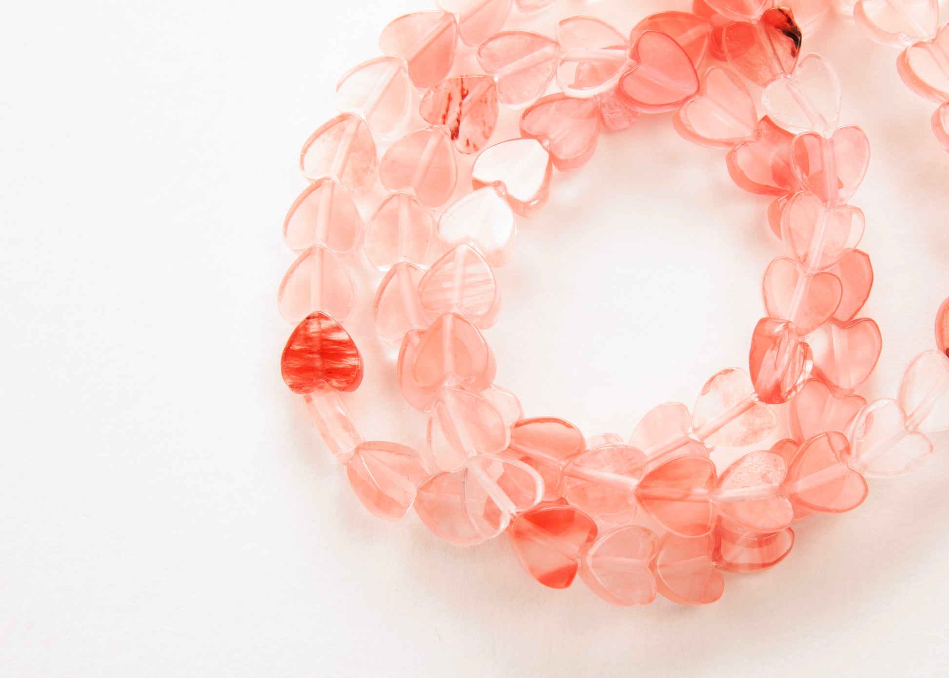 Plan view of a Cherry Quartz heart bead necklace on a white background 
