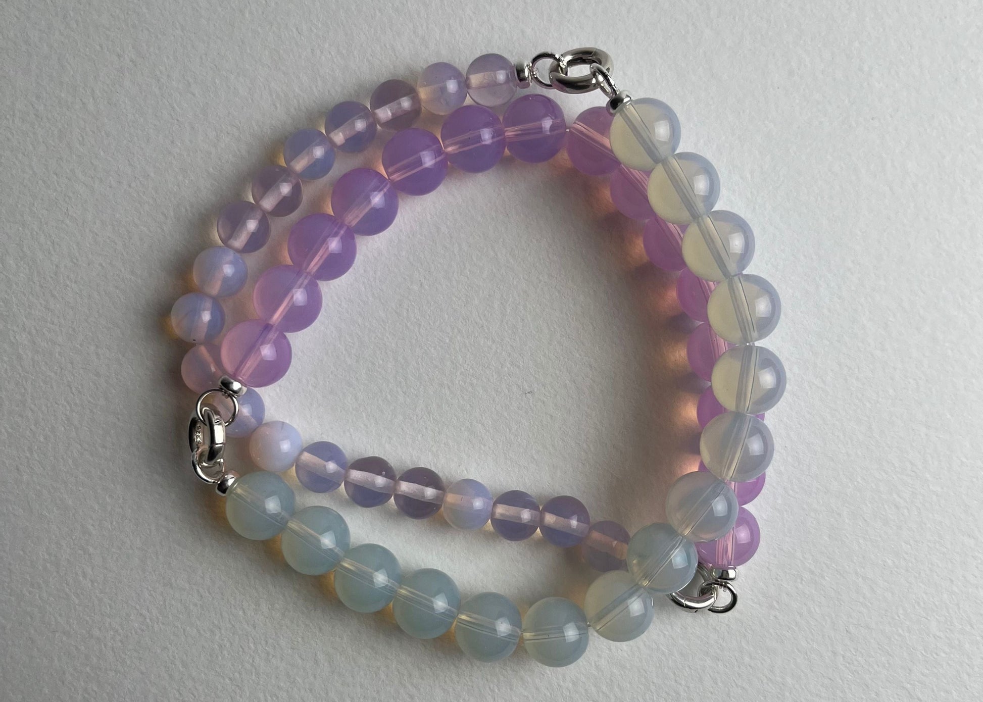 Overhead of a closed Oplaite beaded necklace made of three chainlets on a white background