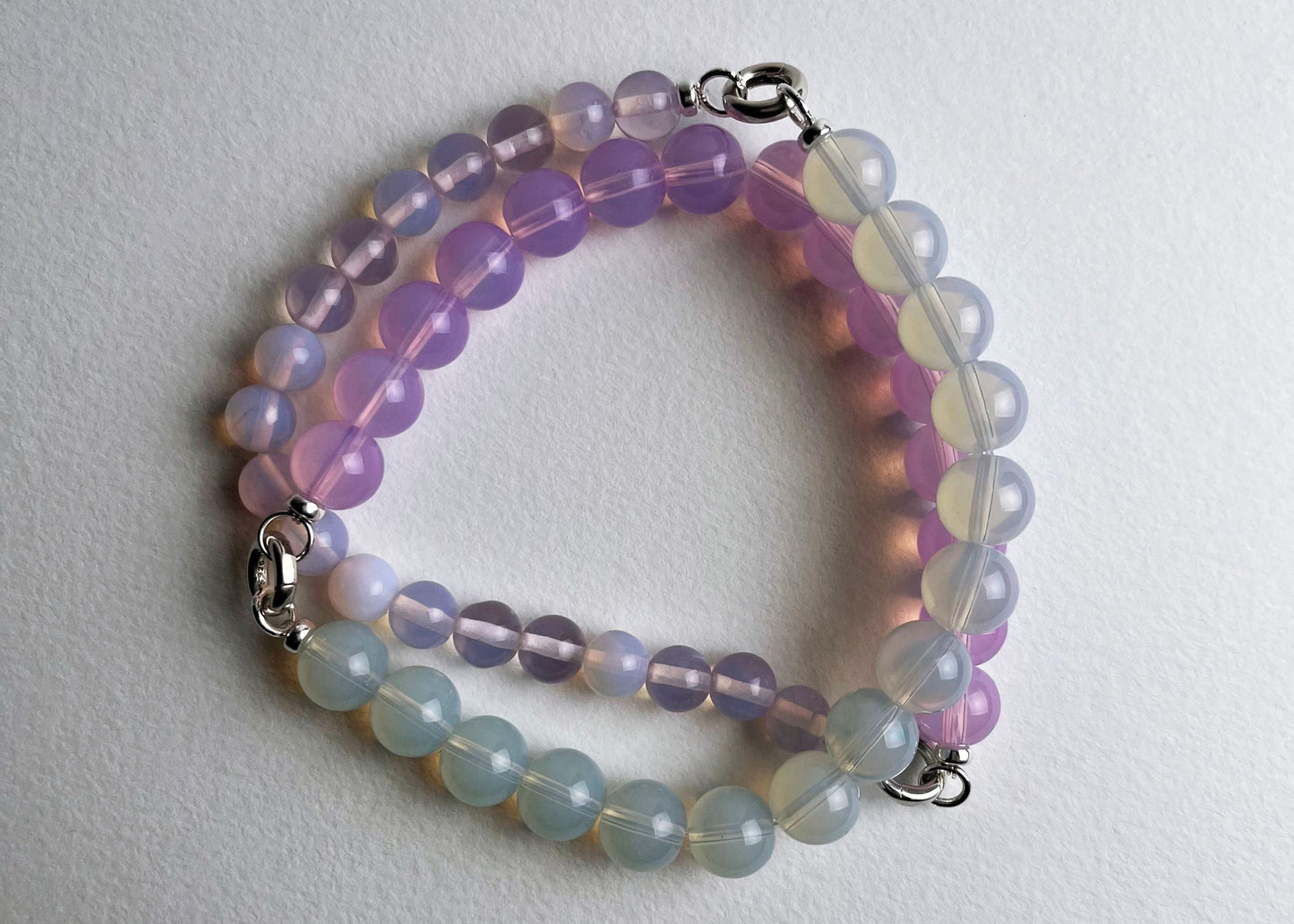 Overhead view of a Opalite beaded necklace made with chainlets with Sterling Silver open loop ends on a white background