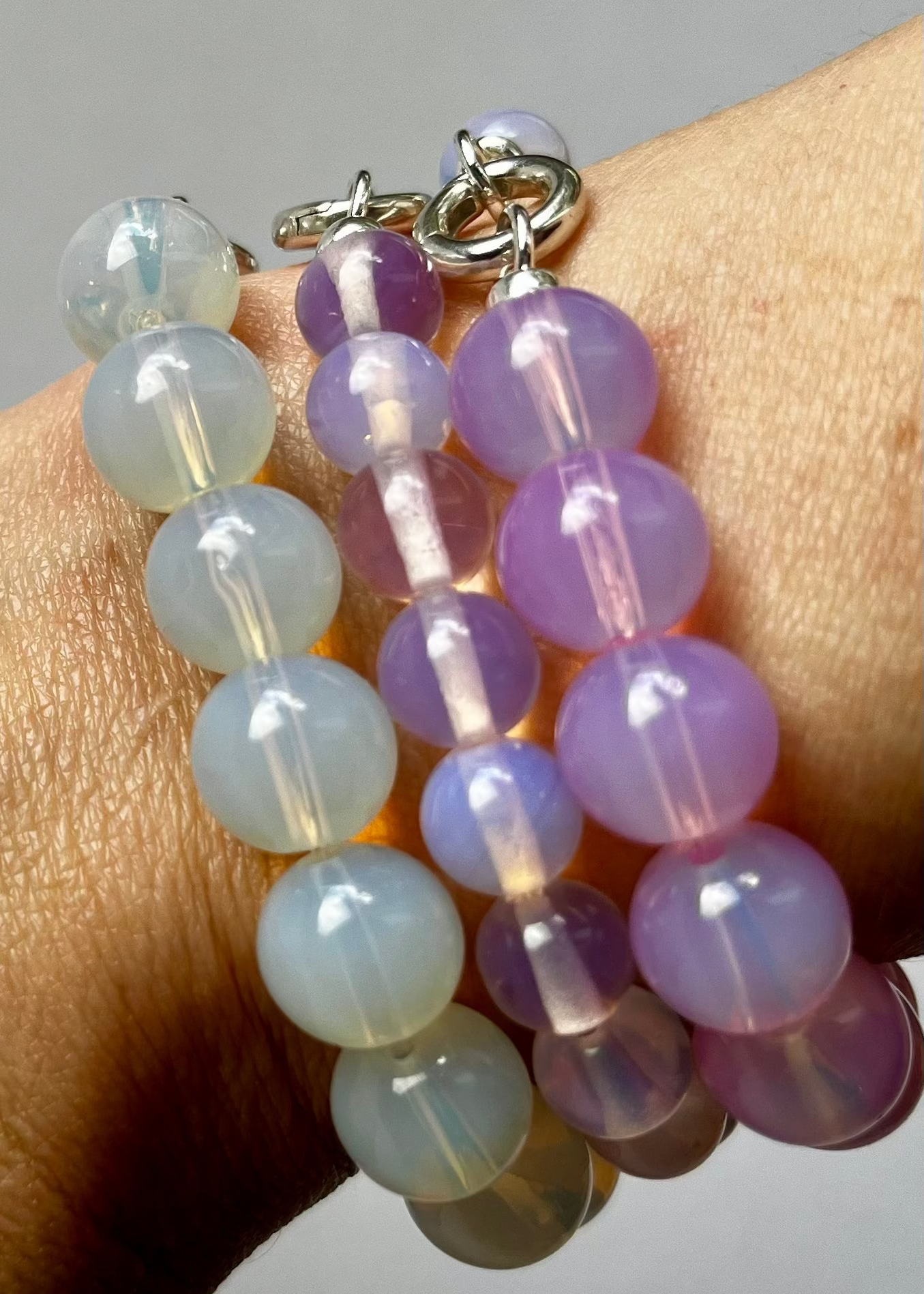 Detail of wrist with bracelet stack of three Opalite beaded chainlets in three different colours