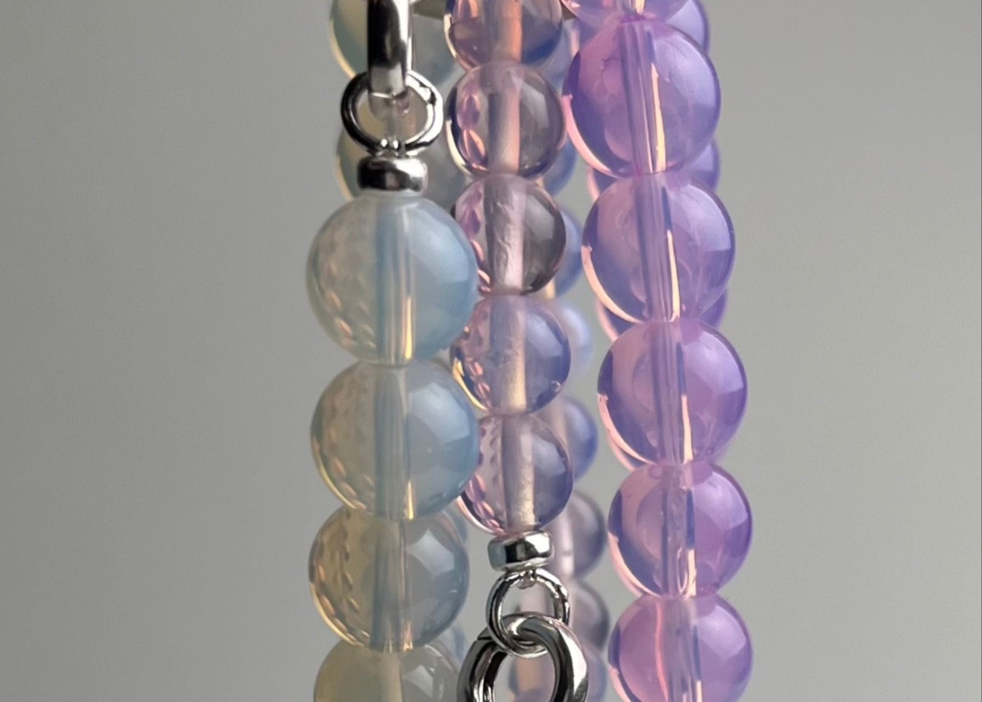 Opalite closed beaded chainlets in 3 colours hanging from a metal hook on a white background