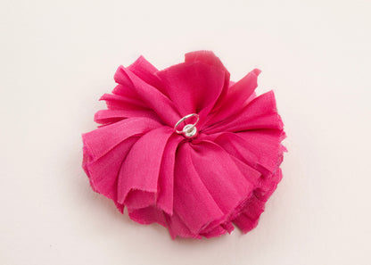 Back view of a fuchsia silk flower charm with sterling silver loop ending on a white background.
