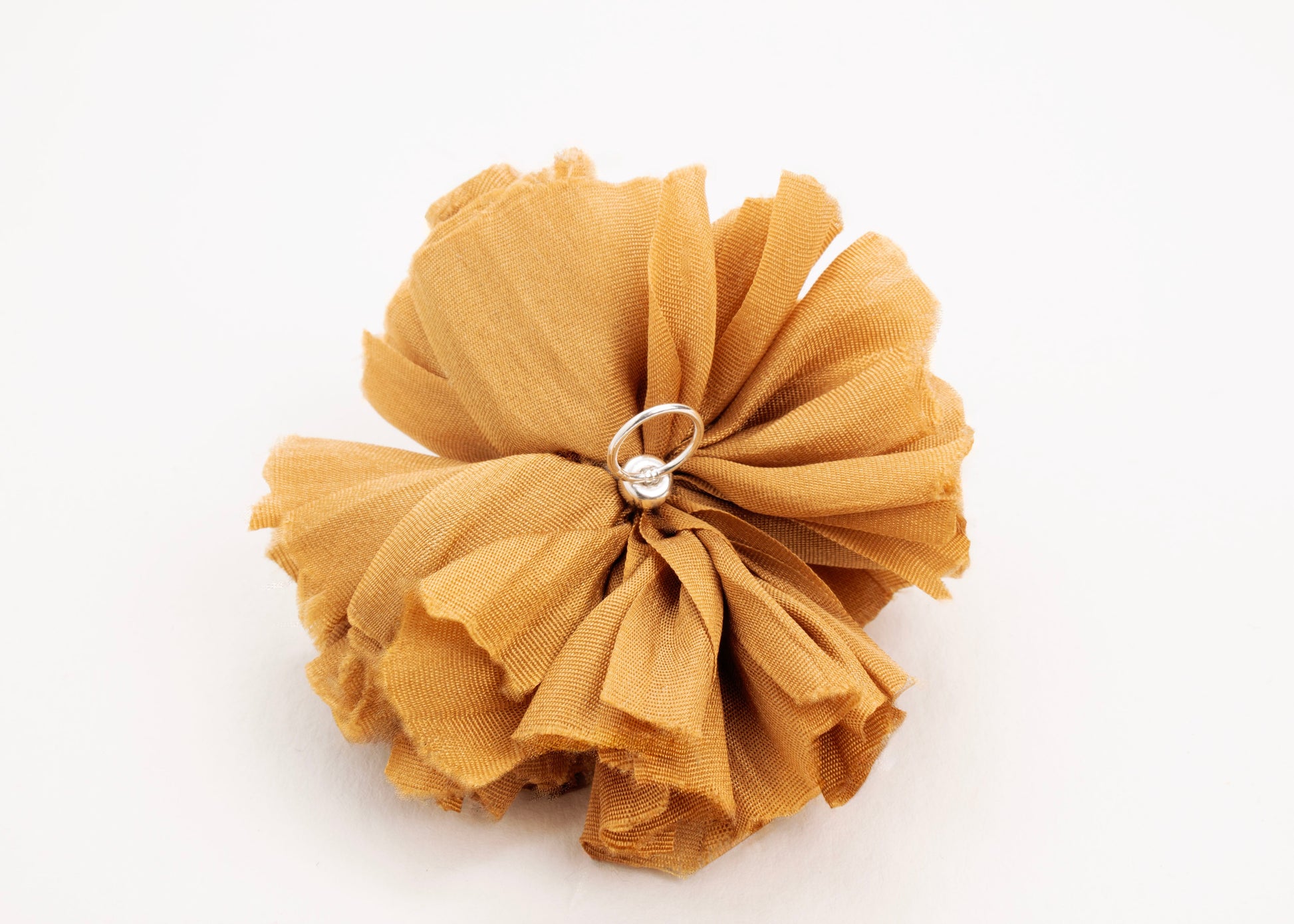 Back view of a gold silk flower charm with sterling silver loop ending on a white background.