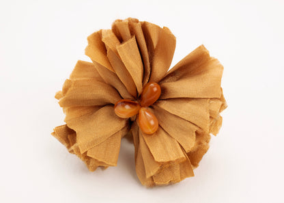 Front view of a gold silk flower charm with glass detail in center on a white background.