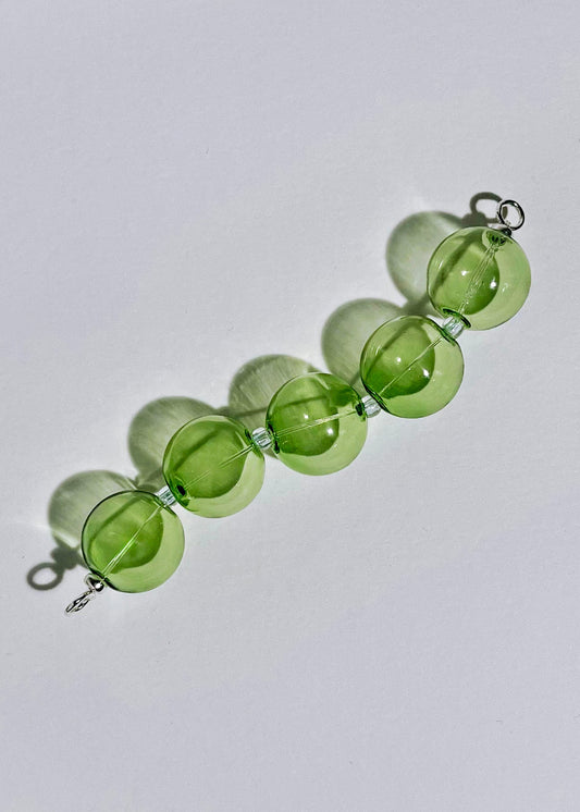 Overhead view of a green chunky bead drop with Sterling Silver endings in a light grey background