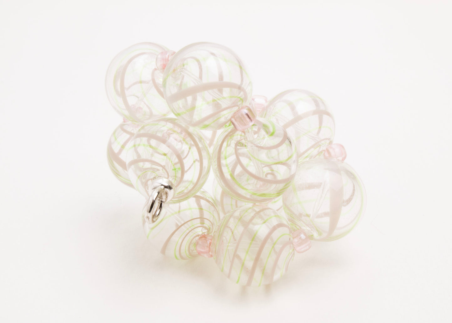 Close up front view of a clear blown glass bead strand with green and pink swirl and pink glass separators tied on a knot on a white background