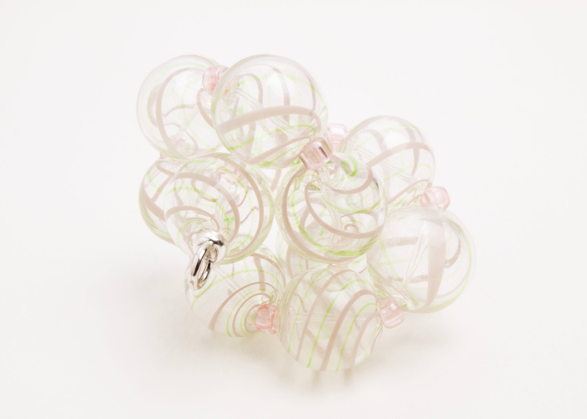 Close up front view of a clear blown glass bead strand with green and pink swirl and pink glass separators tied on a knot on a white background