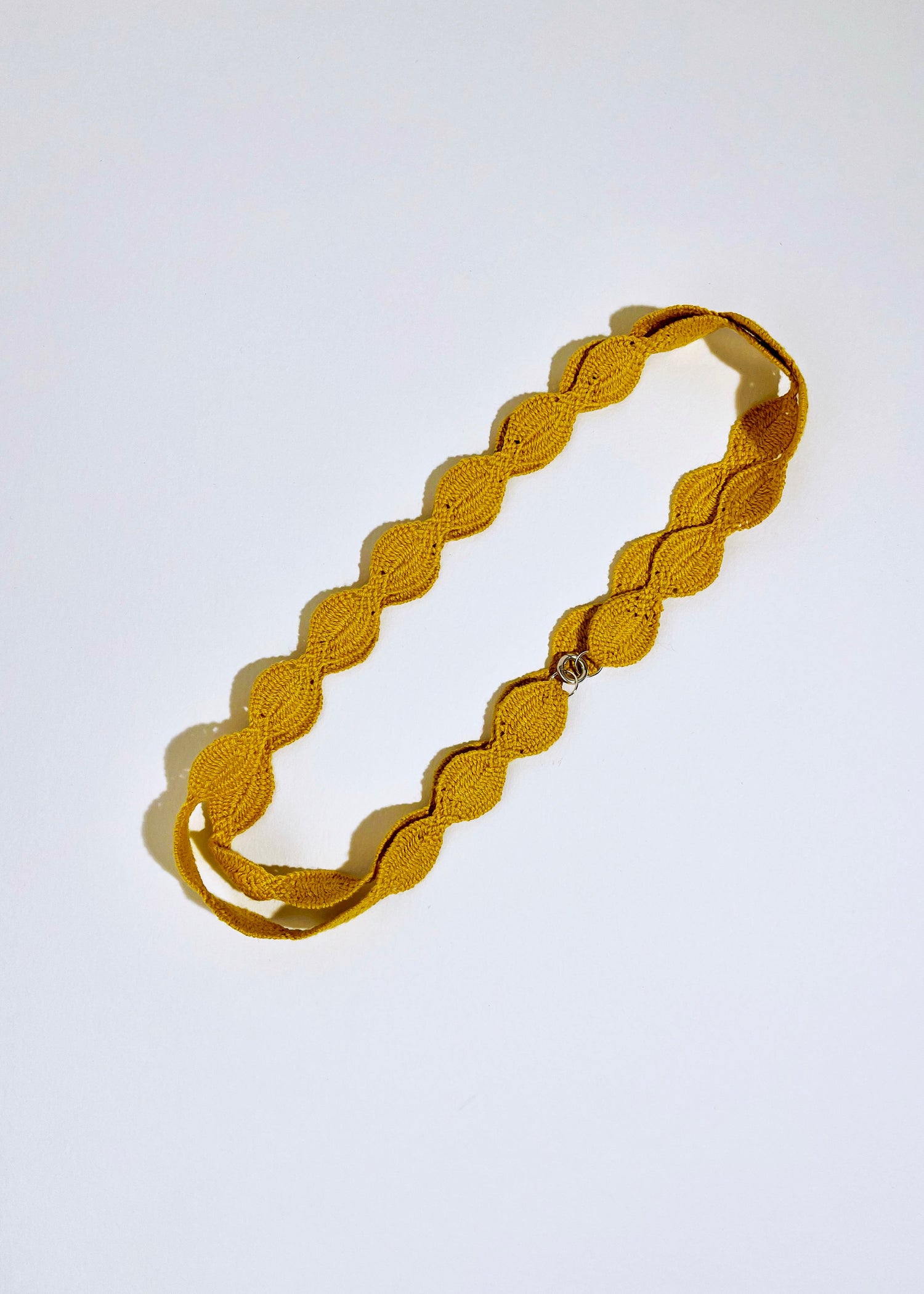 Overhead view of a cotton woven necklace in a double loop with sterling silver endings on a white background