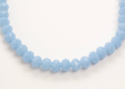 Close up of the drop detail of a light_blue_glass_rondelles_bead_strand_on a white background