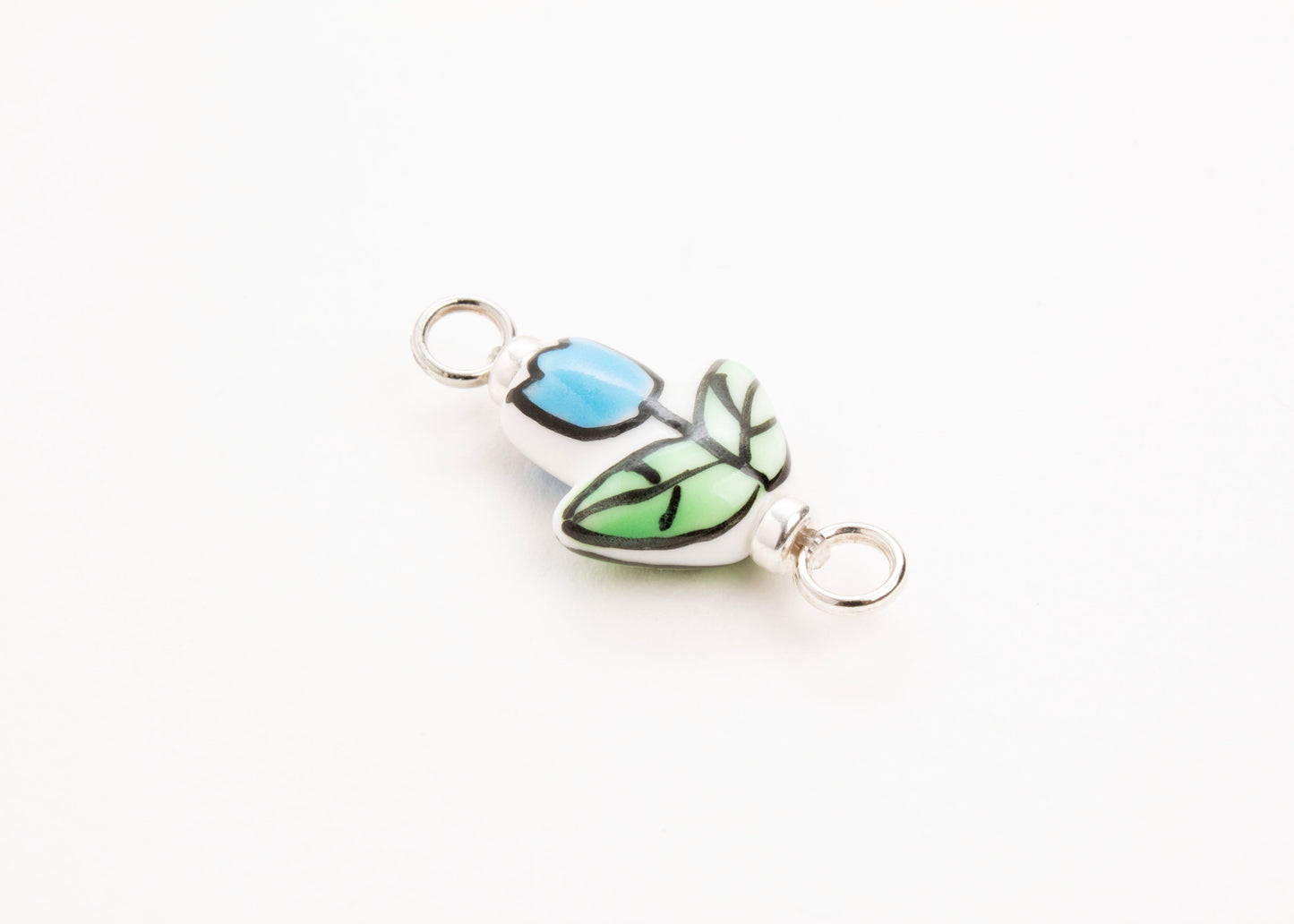 Side diagonal close up of a handprinted light blue_hand painted porcelain_tulip_charm_on a white background
