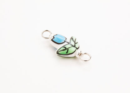 Side diagonal close up of a handprinted light blue_hand painted porcelain_tulip_charm_on a white background