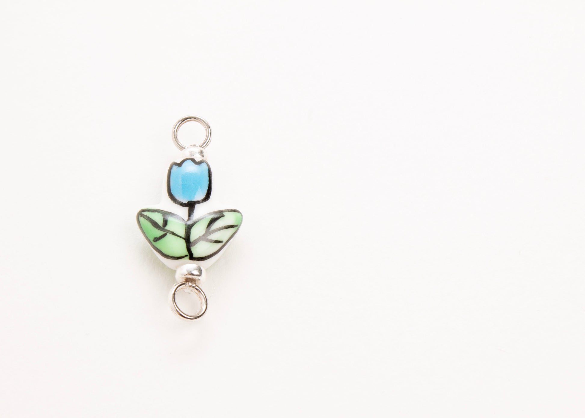 Front close up of a hand painted light blue_hand painted porcelain_tulip_charm_on a white background