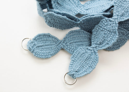 Close up of Sterling Silver looped endings of a light blue cotton woven ovals necklace on a white background. 