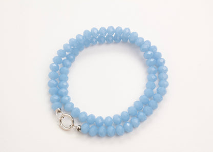 Plan_view of a Light_blue_rondelles_glass_bead_strand_wrapped_in_two_loops_on a white background.
