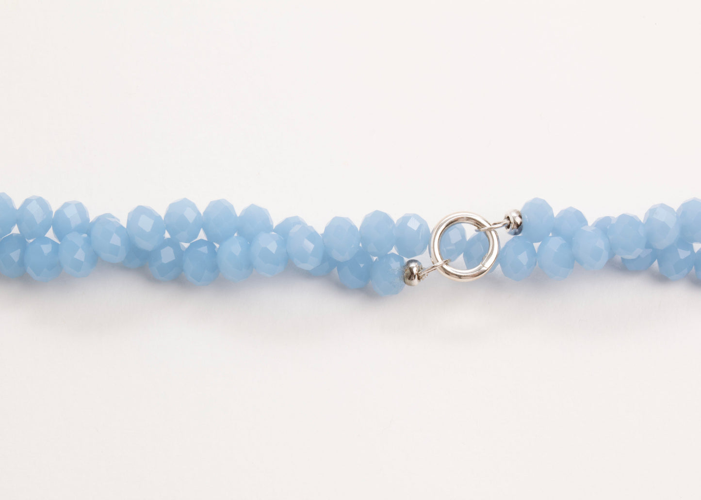 Plan view of a light_blue_glass_beads_strand_closed_twisted_on a white background