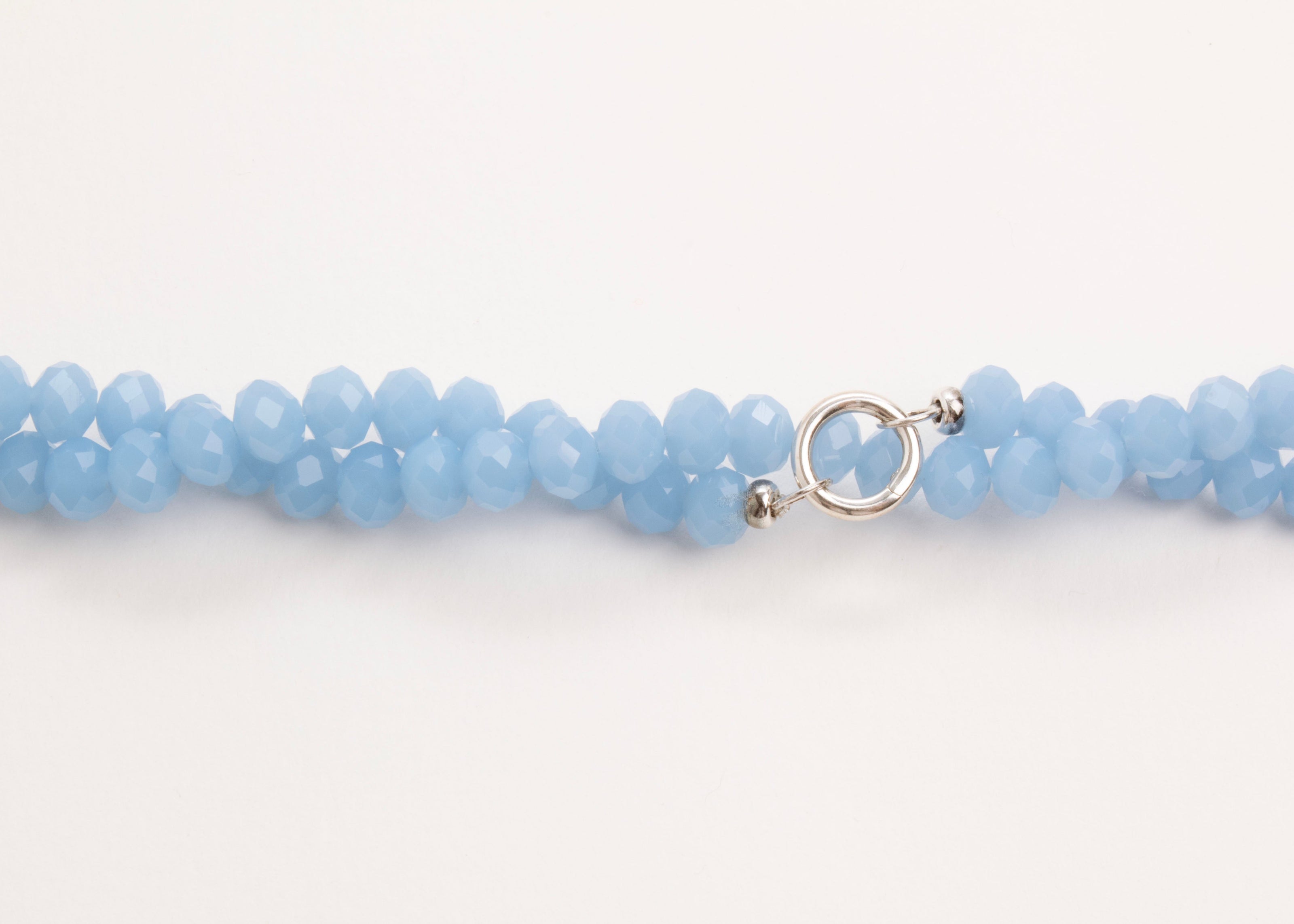 Plan view of a light_blue_glass_beads_strand_closed_twisted_on a white background