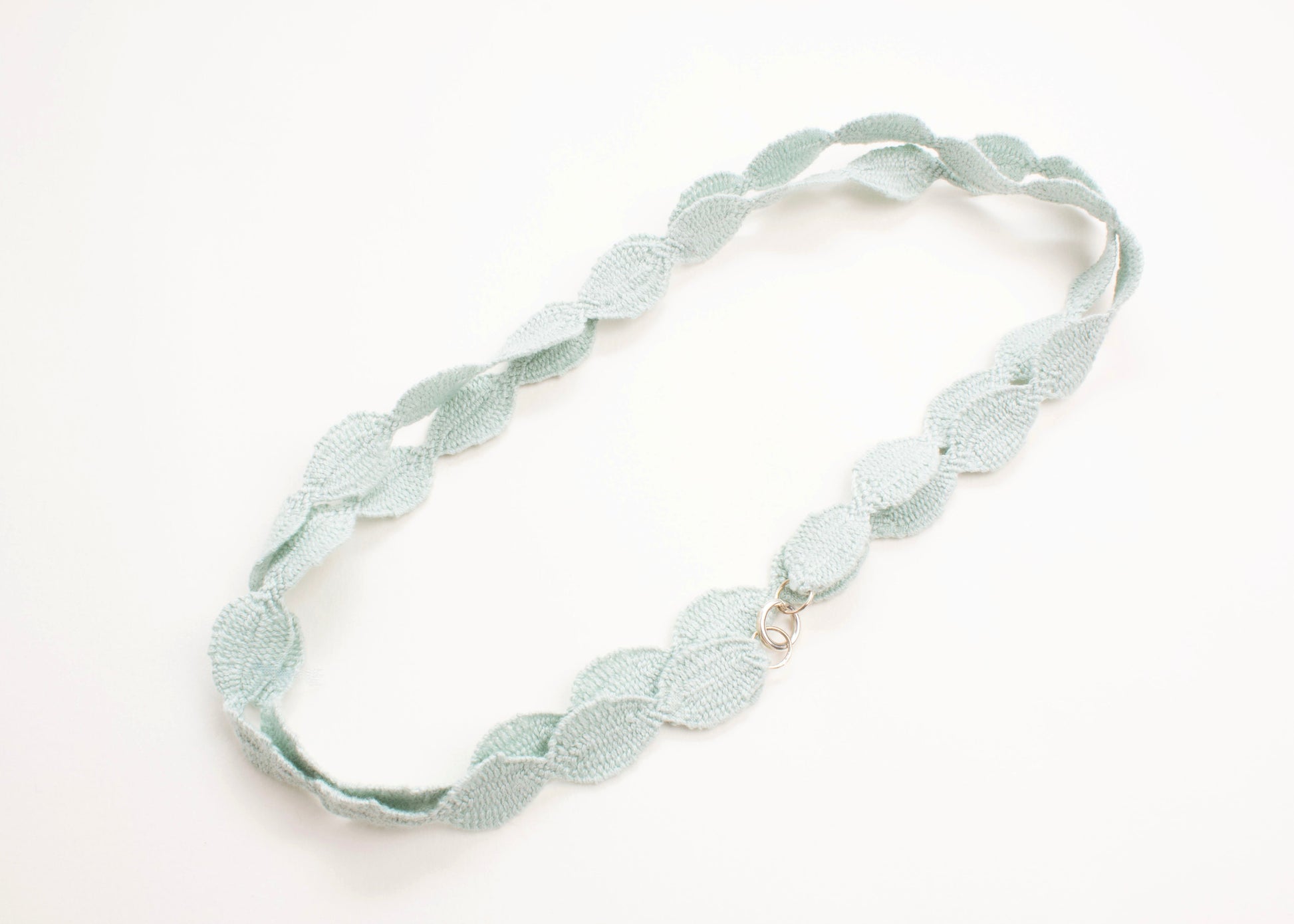 Plan view of a light green cotton ovals necklace wrapped in two loops on a white background