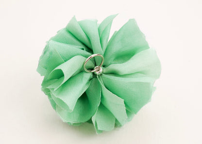 Back view of a light green silk flower charm with sterling silver loop ending on a white background.