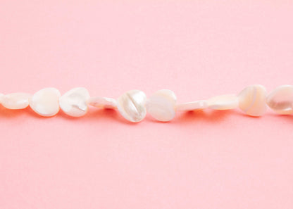 Front view beads detail of a MOP heart beads necklace on a pink background