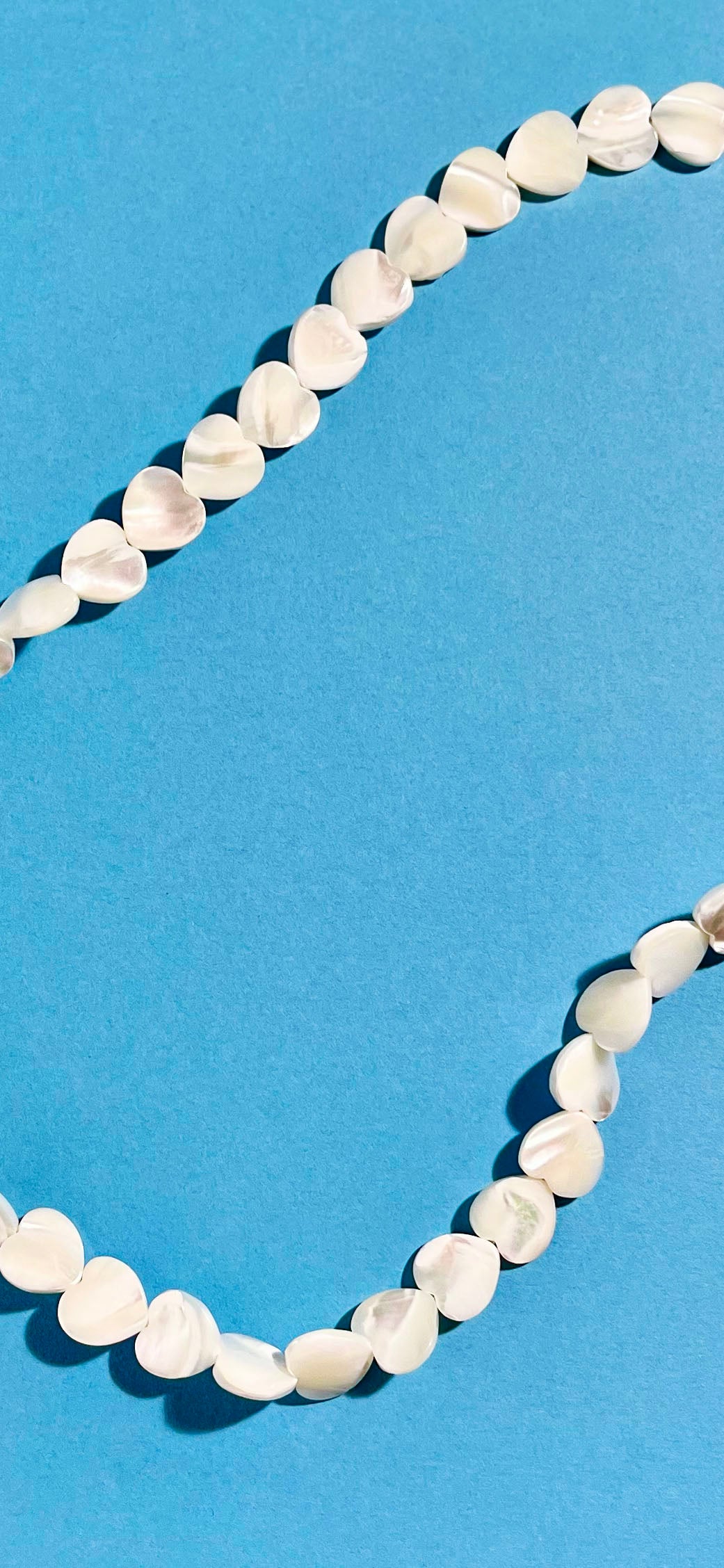 Overhead view of MOP heart shaped carved beads necklace strands 