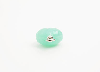 Close up of end of green glass heart charm placed on white background.
