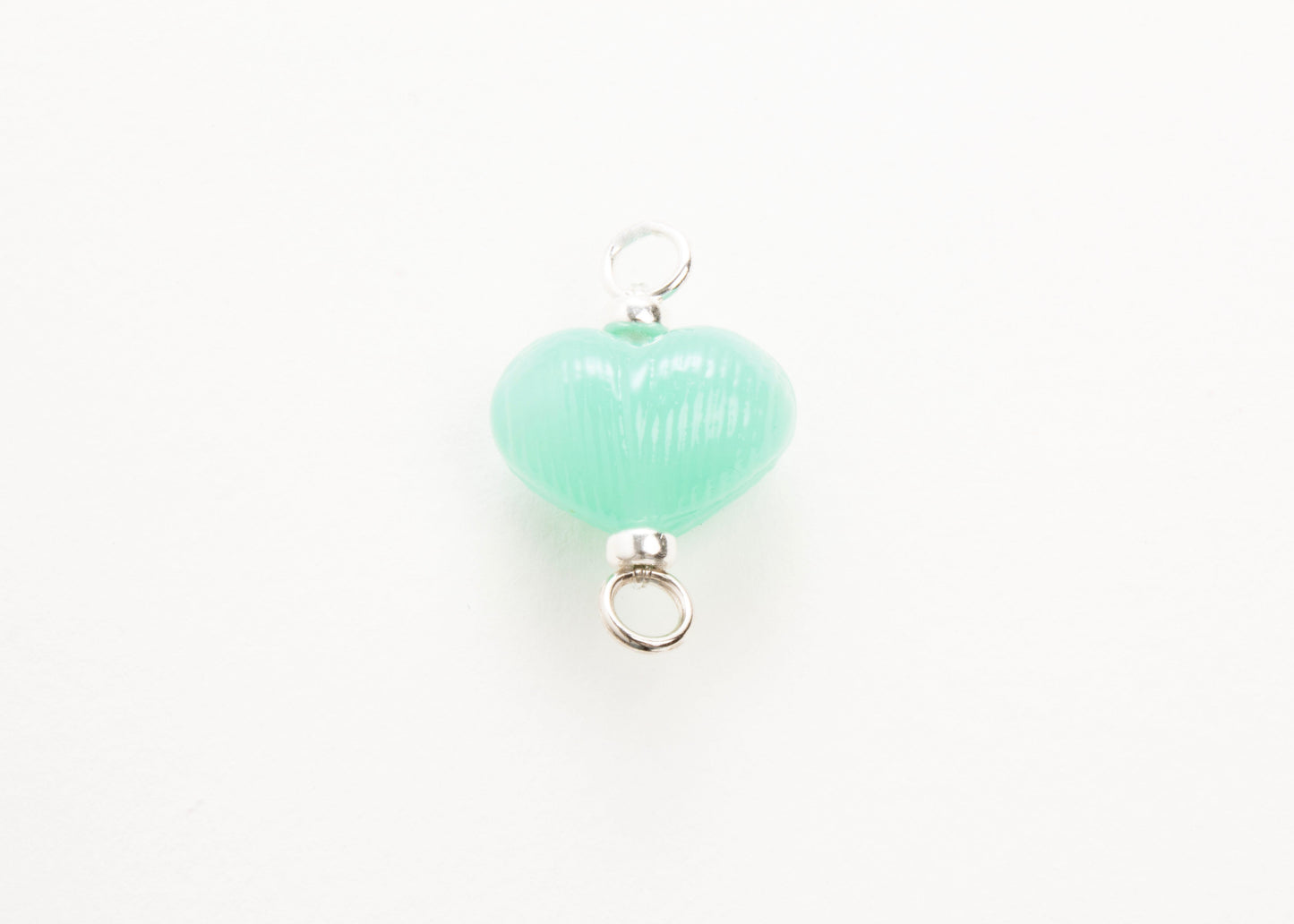 Front plan view of mint glass heart charm placed on white background.