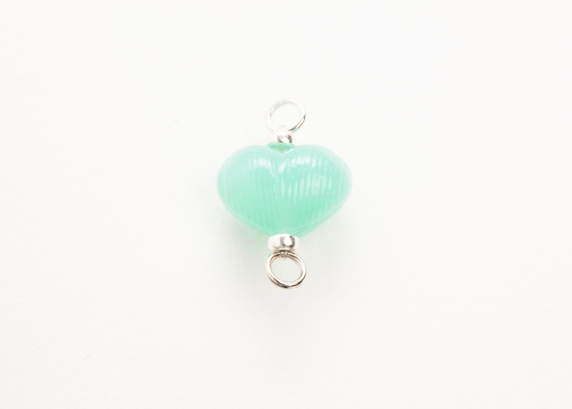 Front plan view of mint glass heart charm placed on white background.
