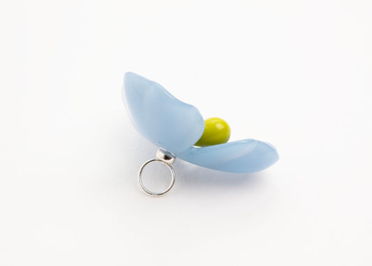 Back left side close up of a light blue resin_flower charm with celery green glass bead detail_and  a Sterling Silver looped ending on a white background.