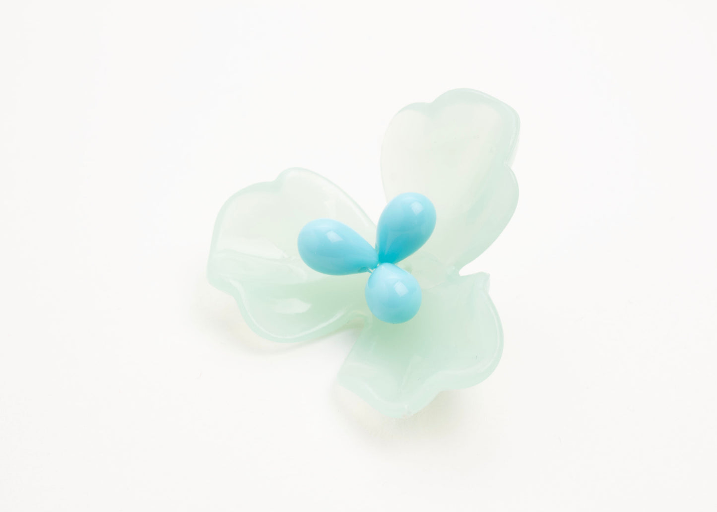 Front view close up of a mint green resin_flower charm with light blue glass bead detail_and a Sterling Silver looped ending on a white background