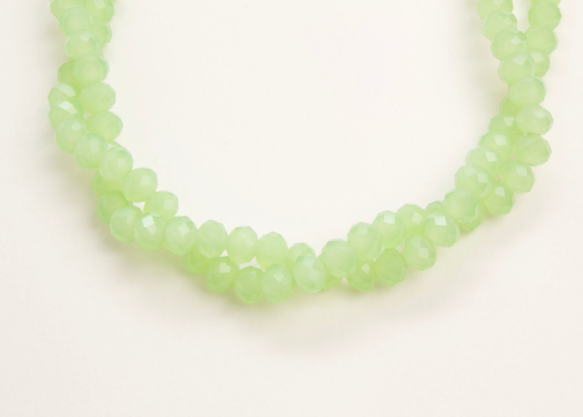 Close up of the drop detail of a mint_green_glass_rondelles_bead_twisted_strand_on a white background