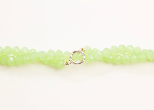 Close up of a mint_green_rondelle_glass_bead_strands_twisted_on a white background