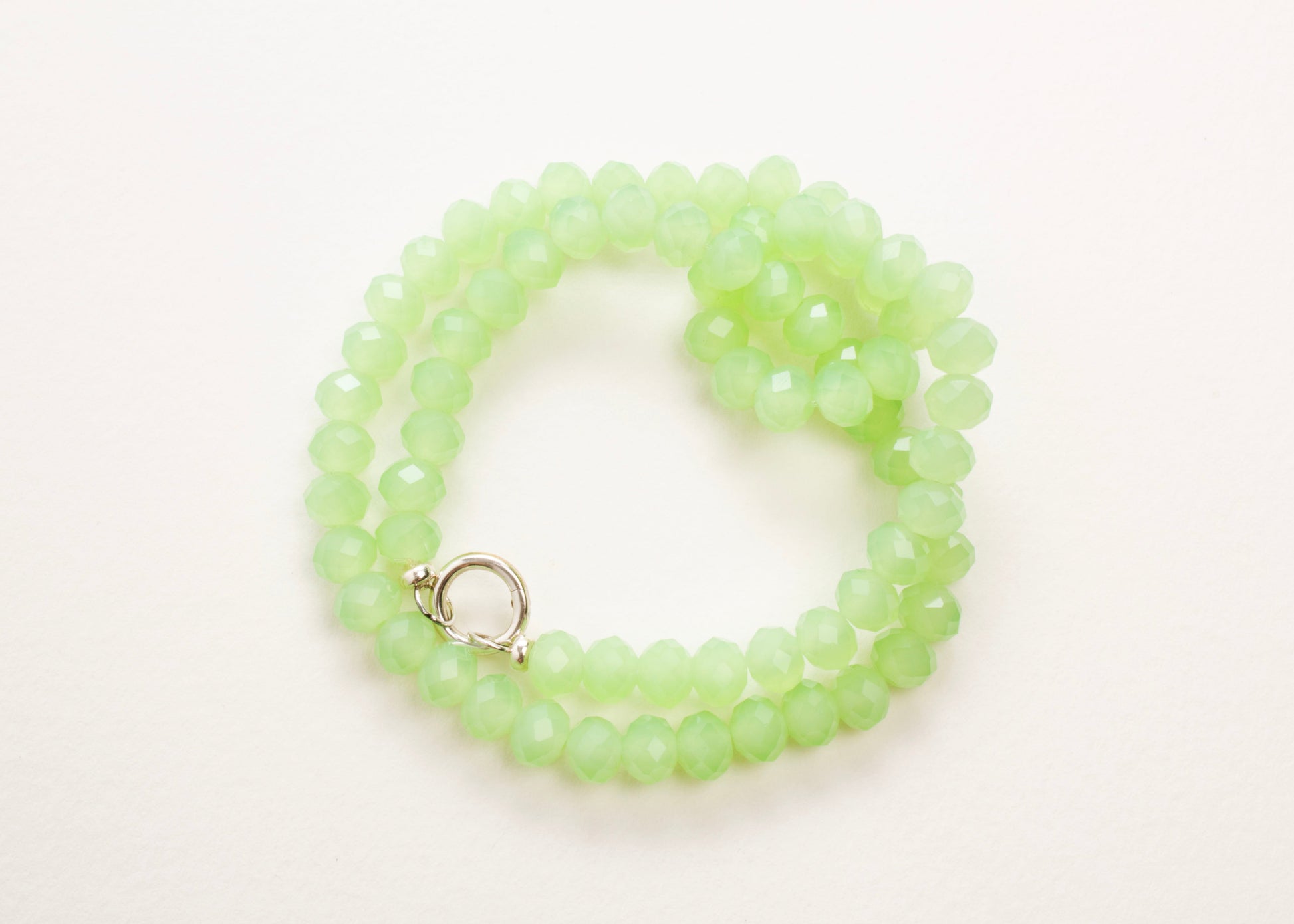 Plan_view of a mint green_rondelles_glass_bead_strand_wrapped_in_two_loops_on a white background.