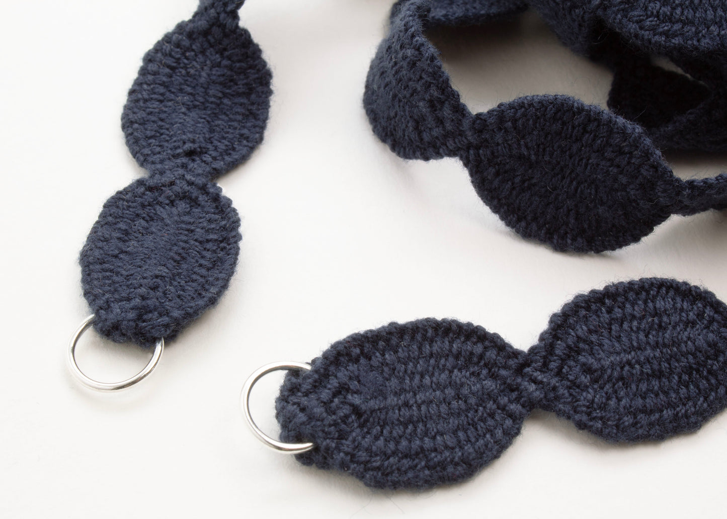 Close up of Sterling Silver looped endings of a light blue cotton woven ovals necklace on a white background. 